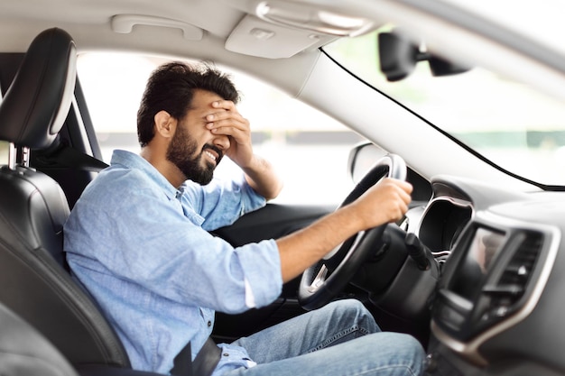 Un joven cansado y molesto del Medio Oriente está conduciendo un auto