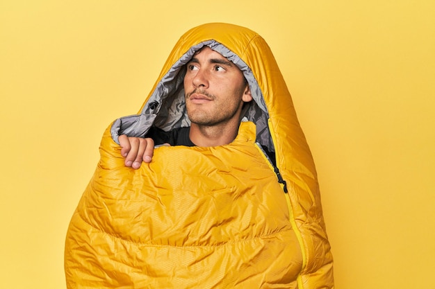 Joven cansado en un saco de dormir en amarillo