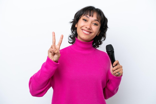 Joven cantante argentina aislada de fondo blanco sonriendo y mostrando el signo de la victoria