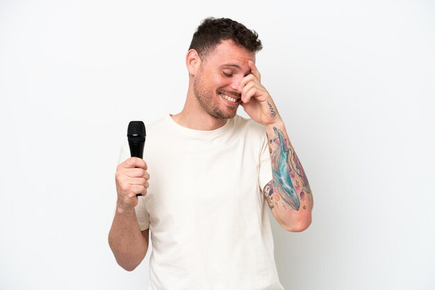 Joven cantante caucásico recogiendo un micrófono aislado de fondo blanco riéndose