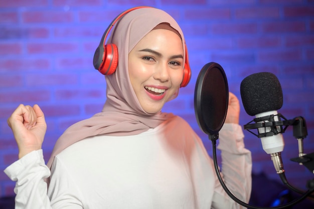 Una joven cantante musulmana sonriente con auriculares con micrófono