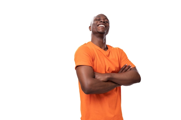 Joven carismático hombre africano fuerte con camiseta naranja aislado sobre fondo blanco con espacio para copiar
