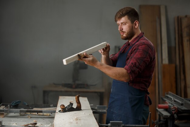 Joven carpintero con un delantal en su taller.