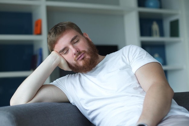 Joven en casa sentado en el sofá cansado bostezando sin dormir aburrido en la sala de estar en casa