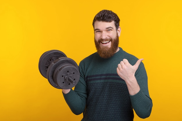 Foto joven en casual mostrando los pulgares hacia arriba y trabajando con mancuernas