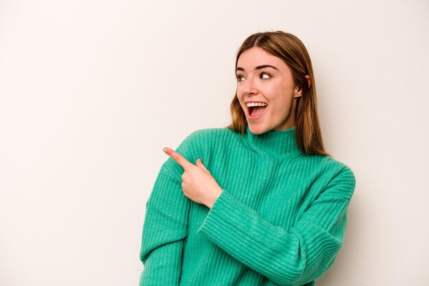 Una joven caucásica aislada de fondo blanco mira a un lado sonriendo alegre y agradable