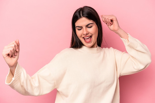 Joven caucásica aislada de fondo rosa bailando y divirtiéndose