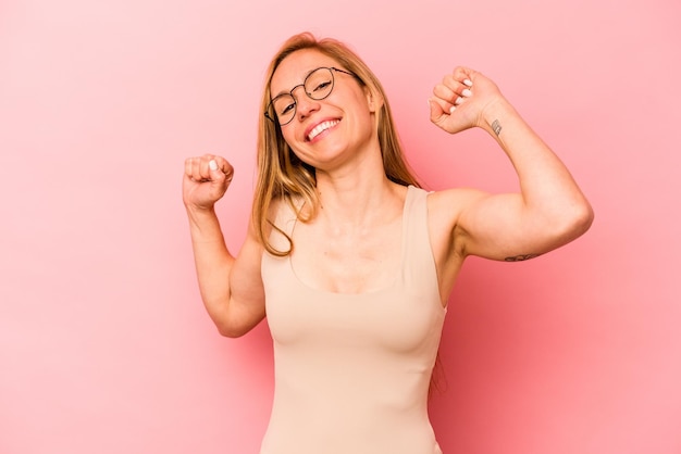 Joven caucásica aislada de fondo rosa celebrando un día especial salta y levanta los brazos con energía