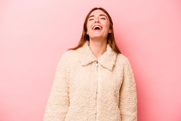 Joven caucásica aislada de fondo rosa relajada y feliz riendo el cuello estirado mostrando los dientes