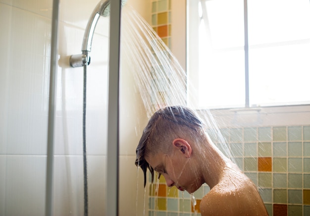 Foto joven caucásica duchándose en el baño