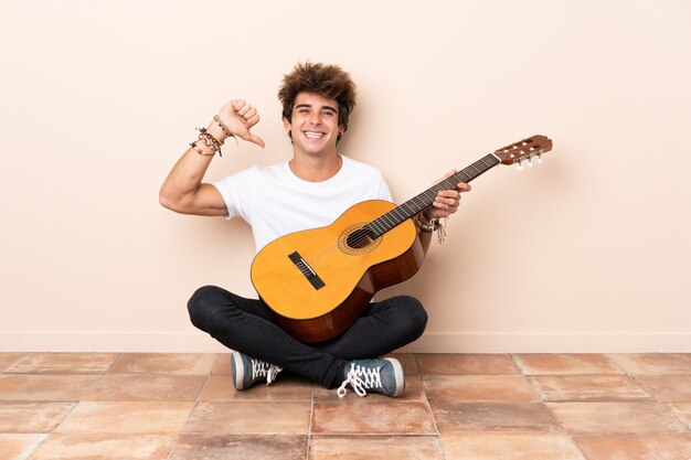 Joven caucásica con una guitarra sentada en el suelo orgullosa y satisfecha