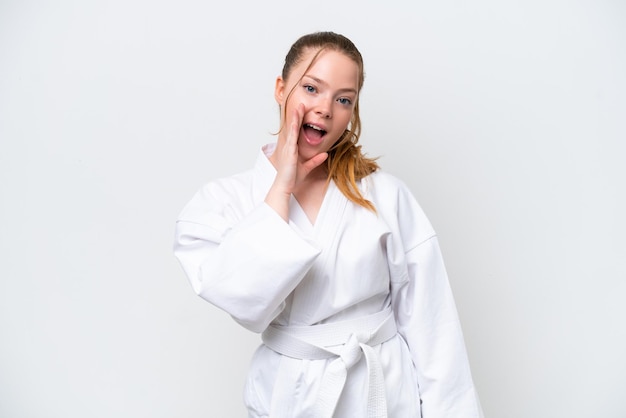 Joven caucásica haciendo karate aislada de fondo blanco gritando con la boca abierta