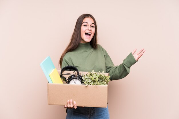 Joven caucásica mudarse a un nuevo hogar aislado recibiendo una agradable sorpresa, emocionado y levantando las manos.