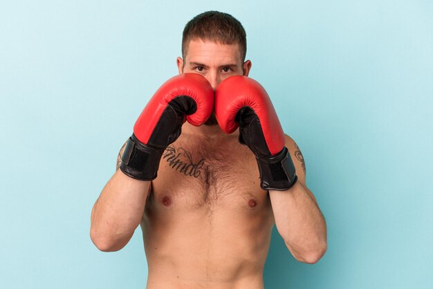 Joven caucásica practicando boxeo aislado sobre fondo azul.