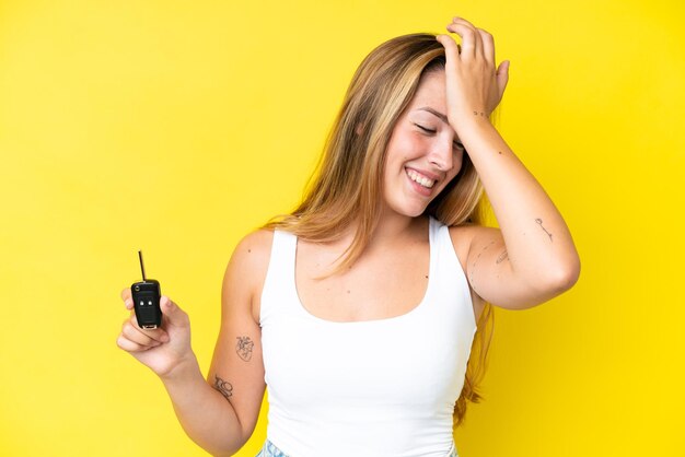 Una joven caucásica que sostiene las llaves del auto aisladas en un fondo amarillo se ha dado cuenta de algo y tiene la intención de encontrar la solución