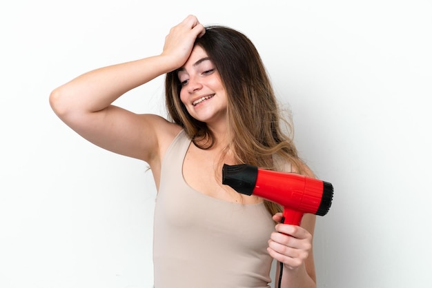 Una joven caucásica que sostiene un secador de pelo aislado de fondo blanco se ha dado cuenta de algo y tiene la intención de encontrar la solución