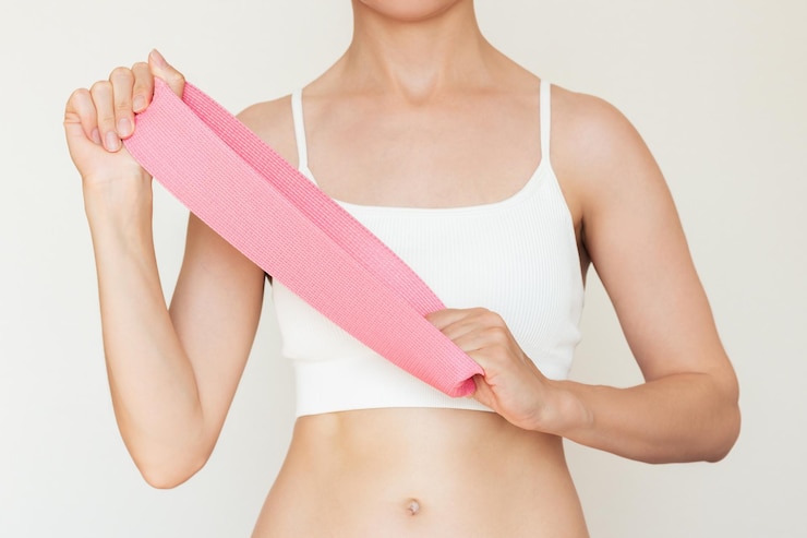 Foto una joven caucásica con ropa blanca sosteniendo una banda elástica rosa para la aptitud en casa