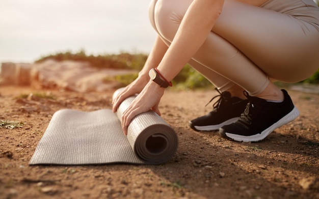 Joven caucásica en ropa deportiva poniendo alfombra en la playa preparándose para entrenar en la playa del océano