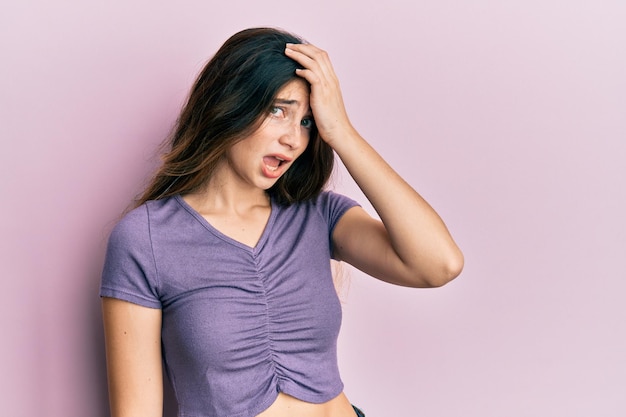 Joven caucásica con ropa informal sorprendida con la mano en la cabeza por error, recuerda el error. olvidé, mal concepto de memoria.