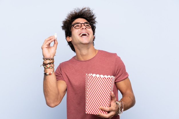 Joven caucásica sobre pared aislada con gafas 3d y sosteniendo un gran cubo de palomitas de maíz