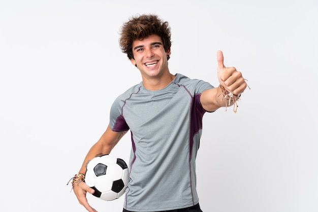Foto joven caucásica sobre pared blanca aislada con balón de fútbol y con el pulgar hacia arriba