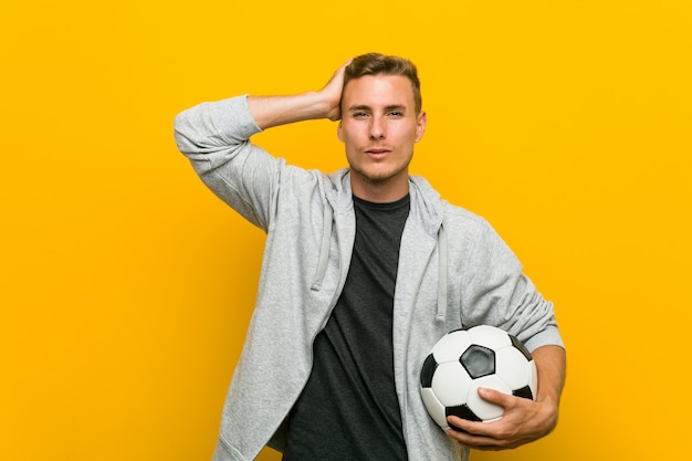 Joven caucásica sosteniendo un balón de fútbol sorprendido, ella ha recordado una reunión importante.