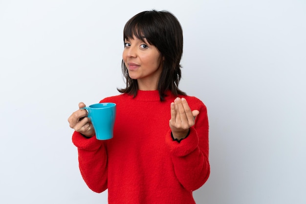 Joven caucásica sosteniendo una taza de café aislada de fondo blanco invitando a venir con la mano Feliz de que hayas venido