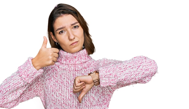 Foto joven caucásica con suéter de invierno de lana haciendo pulgares hacia arriba y hacia abajo, expresión de desacuerdo y acuerdo. conflicto loco