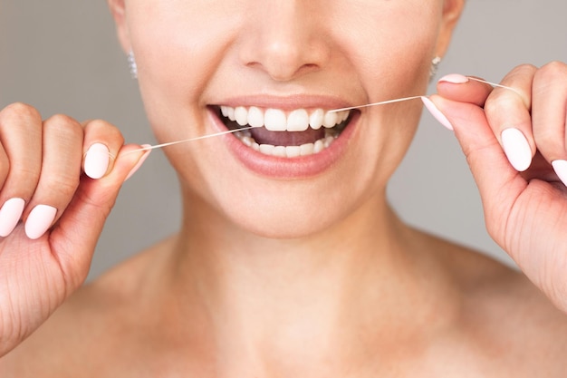 Una joven caucásica usa hilo dental para la higiene bucal y dientes sanos. De cerca