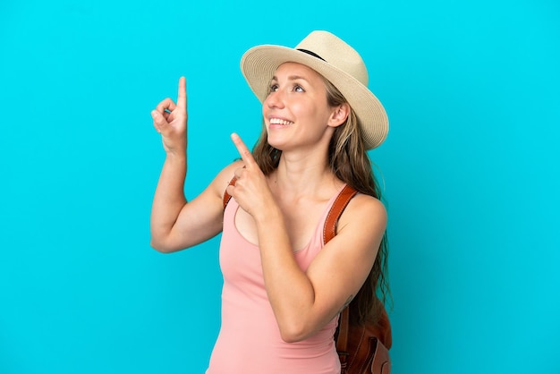 Joven caucásica en vacaciones de verano aislada de fondo azul señalando con el dedo índice una gran idea