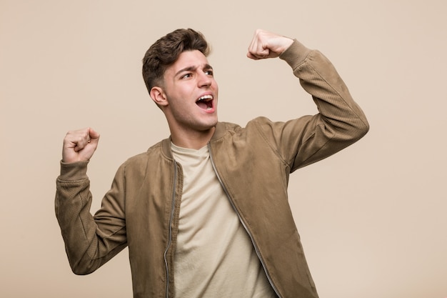 Joven caucásica vistiendo una chaqueta marrón levantando el puño después de una victoria