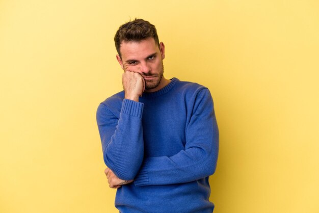 Joven caucásico aislado de fondo amarillo cansado de una tarea repetitiva.