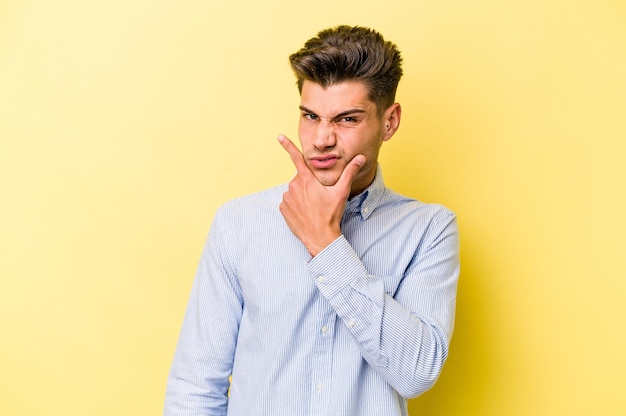 Joven caucásico aislado de fondo amarillo contemplando, planeando una estrategia, pensando en el camino de un negocio.