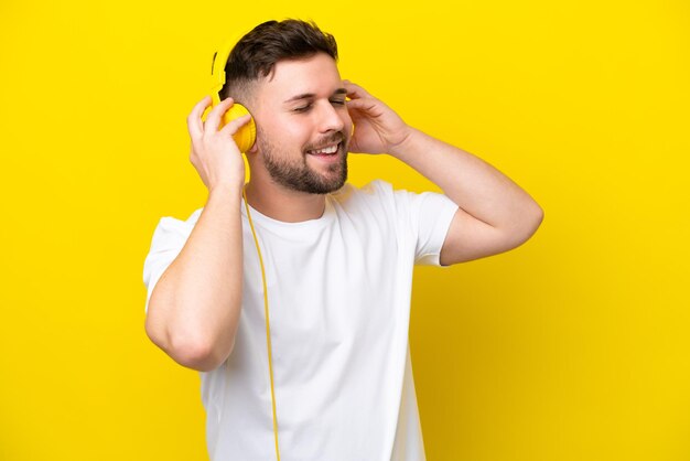 Joven caucásico aislado de fondo amarillo escuchando música y cantando