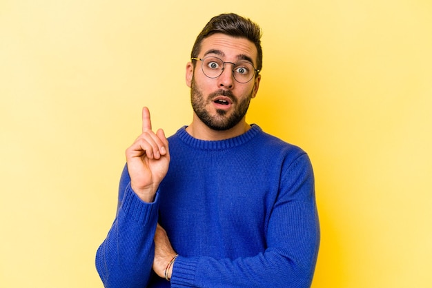 Joven caucásico aislado de fondo amarillo que tiene una gran idea de concepto de creatividad