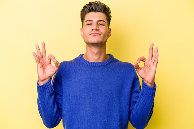 Un joven caucásico aislado de fondo amarillo se relaja después de un duro día de trabajo, ella está haciendo yoga.