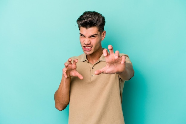 Joven caucásico aislado de fondo azul mostrando garras imitando un gesto agresivo de gato