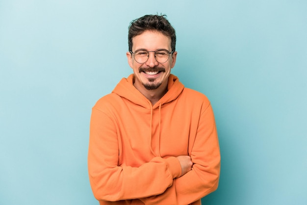 Joven caucásico aislado de fondo azul riendo y divirtiéndose