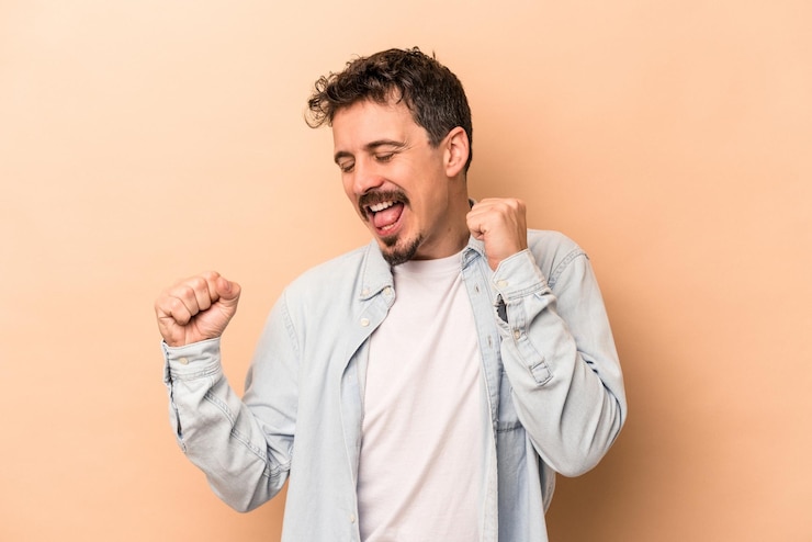 Foto joven caucásico aislado de fondo beige bailando y divirtiéndose.