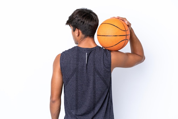 Joven caucásico aislado de fondo blanco jugando baloncesto en posición trasera