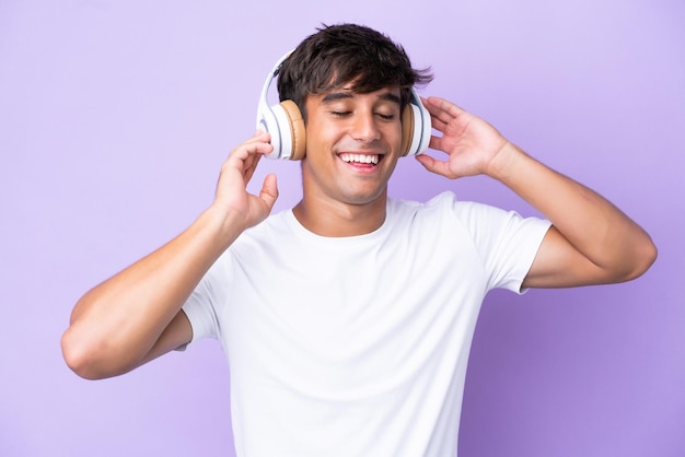 Joven caucásico aislado de fondo morado escuchando música y cantando