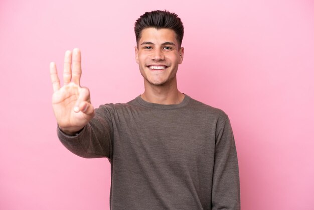 Joven caucásico aislado de fondo rosa feliz y contando tres con los dedos