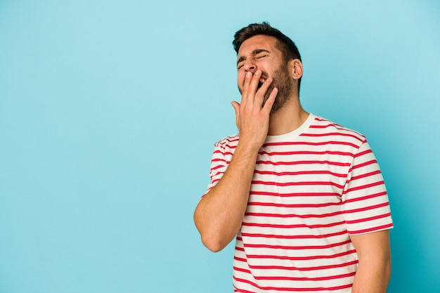 Joven caucásico aislado en la pared azul riendo feliz, despreocupada, natural emoción