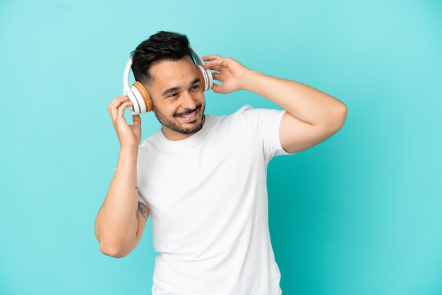 Joven caucásico aislado sobre fondo azul escuchando música y cantando