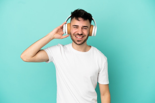 Joven caucásico aislado sobre fondo azul escuchando música