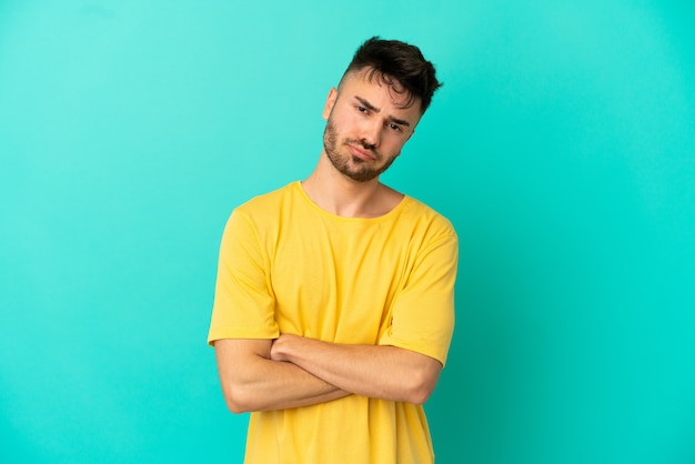 Foto joven caucásico aislado sobre fondo azul sintiéndose molesto