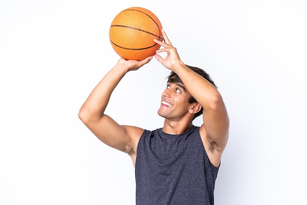 Joven caucásico aislado sobre fondo blanco jugando baloncesto