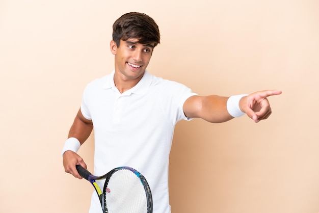 Joven caucásico aislado sobre fondo ocre jugando al tenis