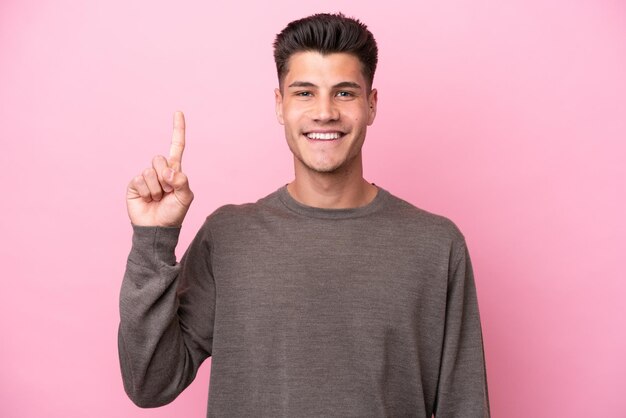 Joven caucásico aislado sobre fondo rosa apuntando hacia una gran idea