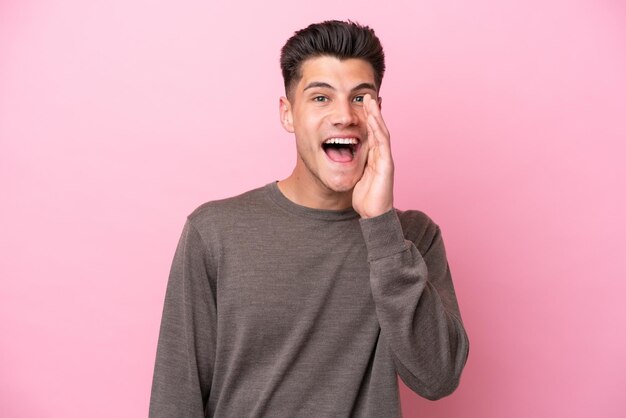 Joven caucásico aislado sobre fondo rosa con sorpresa y expresión facial conmocionada